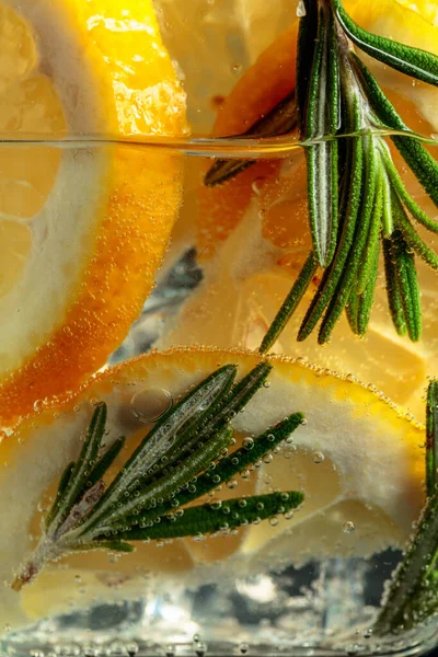 Carbonated drink with lemon slices and rosemary. Macro shot.