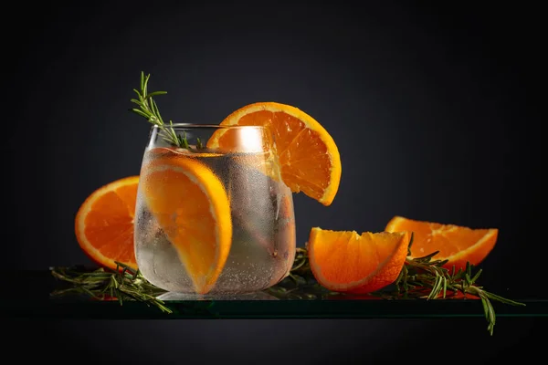 氷とカクテル オレンジ 冷凍ガラスでローズマリー 黒を基調としたアイスリフレッシュドリンク — ストック写真