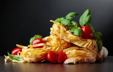 Siyah arka planda domates, sarımsak ve fesleğenli ev yapımı çiğ makarna. Boşluğu kopyala.