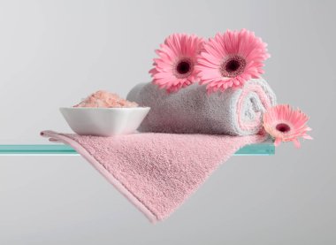 Pembe tuz, çiçek ve havluyla spa kompozisyonu.