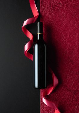 Bottle of red wine with red and pink satin ribbons. Top view.