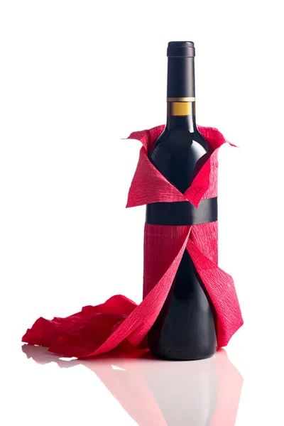 stock image Bottle of red wine wrapped in crepe paper isolated on a white background. The bottle looks like a woman in a red evening dress.