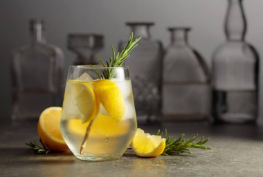 Bardaki taş bir masada buzlu, biberiyeli ve limonlu cin tonik.. 