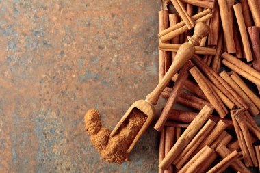 Ahşap kaşıkta tarçın tozu ve paslı metal zeminde tarçın çubukları. Üst Manzara. Boşluğu kopyala.
