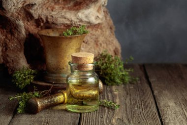 Bottle of thyme essential oil with fresh thyme twigs on an old wooden table. Copy space.