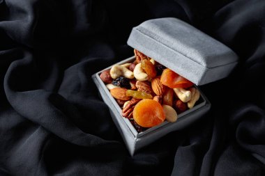 Kurutulmuş meyve ve fındık siyah bir kumaş üzerinde hediye kutusunda..