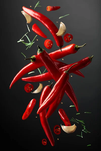 红辣椒 大蒜和迷迭香落在黑色背景上 香料在运动 辛辣食物的概念 — 图库照片