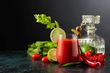 Salatalık, zeytin, limon ve kereviz ile süslenmiş Bloody Mary kokteyli. Siyah arka planda malzemelerle domates suyu. Boşluğu kopyala.