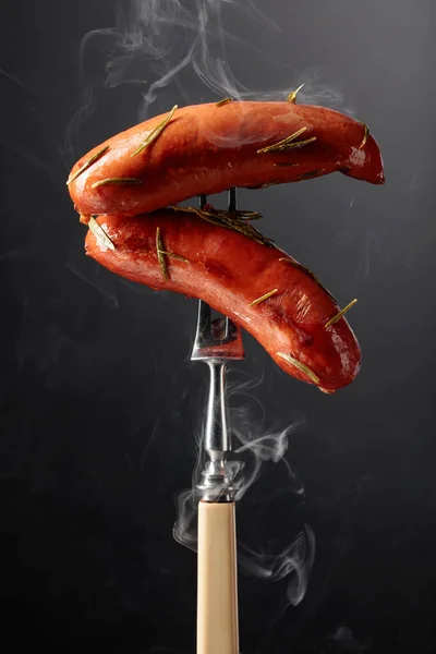 stock image Roasted Bavarian sausages with rosemary on a fork.