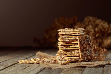 Eski ahşap bir masada ayçiçeği ve keten tohumlu çıtır krakerler. Basit sağlıklı yiyecekler. Boşluğu kopyala.