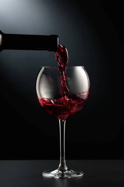 Rode Wijn Gieten Een Wijnglas Een Zwarte Achtergrond — Stockfoto