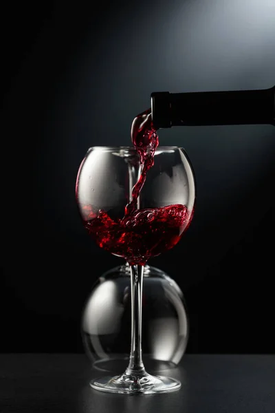 Rode Wijn Een Wijnglas Gieten Een Zwarte Achtergrond Een Omgedraaid — Stockfoto