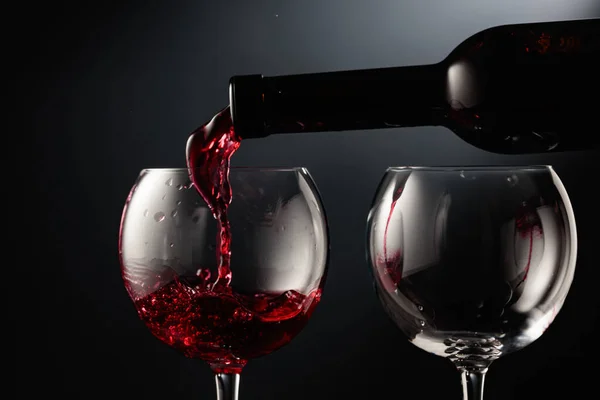 Kırmızı Şarabı Siyah Arka Planda Bir Şarap Bardağına Döküyorum — Stok fotoğraf