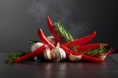 Kırmızı kırmızı biber, sarımsak ve biberiye siyah arka planda. Boşluğu kopyala..