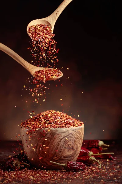 辣椒片倒入一个木制盘子里 辣椒片和干辣椒 背景为褐色 — 图库照片