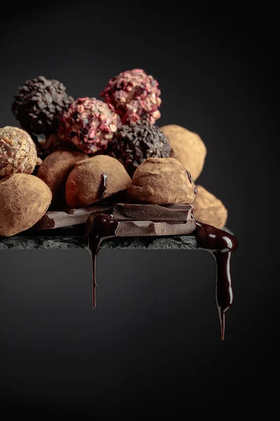 Köstliche Schokoladentrüffel Und Fallende Tropfen Schokoladensauce Auf Schwarzem Hintergrund — Stockfoto