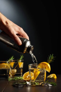 Limonlu ve biberiyeli kokteyl Cin ve Tonik. Barmen bardaktan bardağa bir kokteyl doldurur. Boşluğu kopyala.