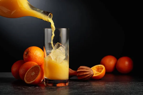 병에서 오렌지 주스를 얼음이 유리잔에 붓는다 — 스톡 사진