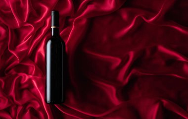 Bottle of red wine on a satin background. Top view.