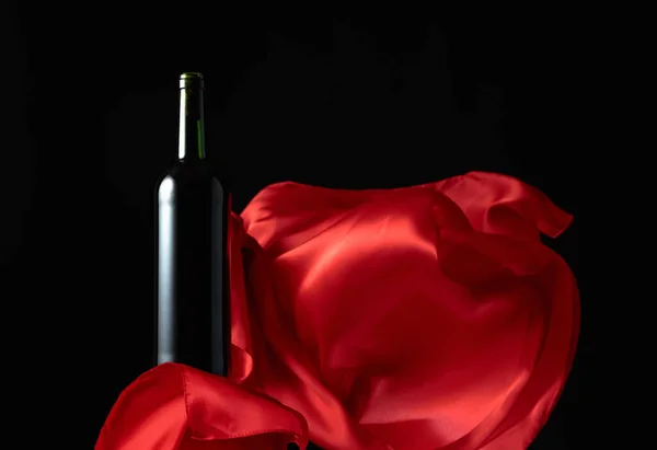 Butelka Czerwonego Wina Trzepotanie Czerwonej Tkaniny Czarnym Tle — Zdjęcie stockowe