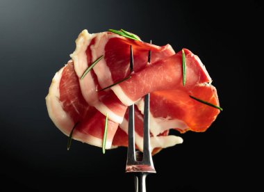 Çatal üzerinde biberiyeli dilimlenmiş jambon, siyah arkaplan, boşluğu kopyala.