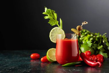 Salatalık, zeytin, limon ve kereviz ile süslenmiş Bloody Mary kokteyli. Siyah arka planda malzemelerle domates suyu. Boşluğu kopyala.