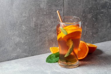 Buzlu çay, naneli ve portakallı. Gri arka planda malzemeleri olan soğuk, ferahlatıcı bir içecek. Boşluğu kopyala.