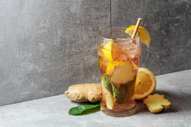 Buzlu çay, nane, zencefil ve limon. Gri arka planda malzemeleri olan soğuk, ferahlatıcı bir içecek. Boşluğu kopyala.