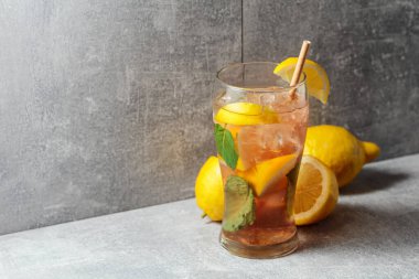 Buzlu çay, naneli ve limonlu. Gri arka planda malzemeleri olan soğuk, ferahlatıcı bir içecek. Boşluğu kopyala.