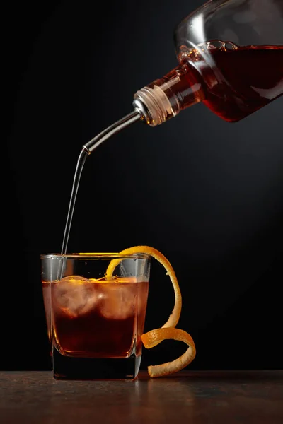アイスとオレンジピールの古いスタイルのカクテル ウイスキーは氷を入れたガラスに注がれる — ストック写真