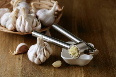 Garlic bulbs and garlic press on an old wooden table. 