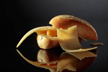 Sandwich with Parmesan cheese on a black reflective background.
