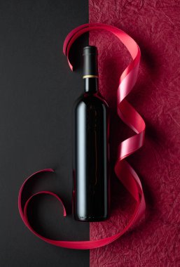 Bottle of red wine with red and pink satin ribbons. Top view.