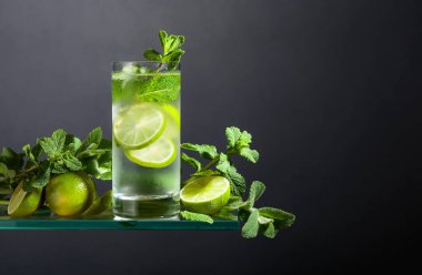 Buzlu, limonlu ve naneli mojito. Siyah arka planda sisli bardakta buzlu içecek. Boşluğu kopyala. 