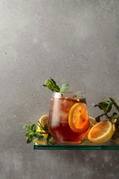 stock image Iced tea with lemon and mint on the background of the grey concrete wall. Copy space.