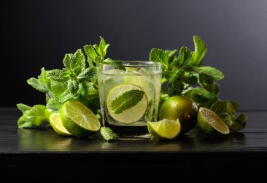 Siyah ahşap bir masada buzlu, limonlu ve naneli mojito..
