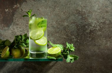 Buzlu, limonlu ve naneli mojito. Eski taştan bir arka planda sisli bir bardakta buzlu içecek. Boşluğu kopyala. 