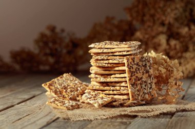 Crispy crackers with sunflower and flax seeds on an old wooden table. Simple healthy food.