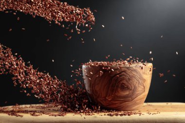 Grains of flaxseed are poured into the wooden bowl. Copy space.