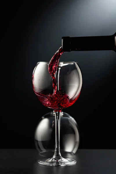 Rode Wijn Een Wijnglas Gieten Een Zwarte Achtergrond Een Omgedraaid — Stockfoto