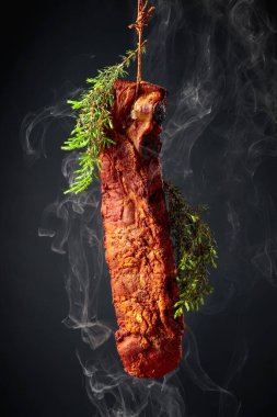 Siyah arka planda ardıç dallarıyla ev yapımı füme domuz pirzolası..