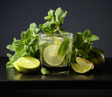 Siyah ahşap bir masada buzlu, limonlu ve naneli mojito..