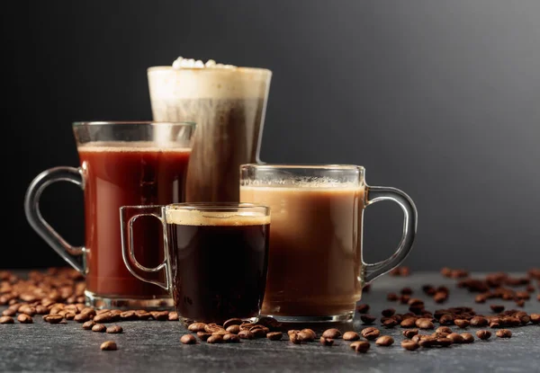 stock image Various coffee and chocolate drinks with scattered coffee beans on a black table.