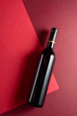 Kırmızı arka planda bir şişe kırmızı şarap. Üst görünüm, alanı kopyala.