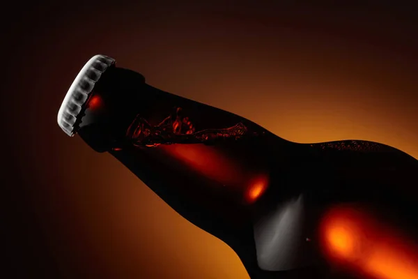 Nahaufnahme Einer Ungeöffneten Bierflasche Orange Hintergrundbeleuchtung — Stockfoto
