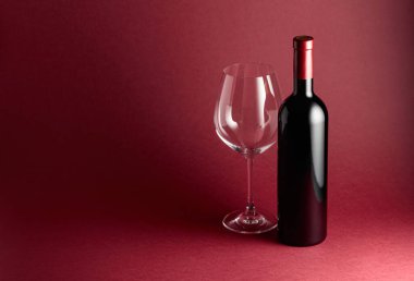 Kırmızı arka planda bir şişe kırmızı şarap. Boşluğu kopyala.