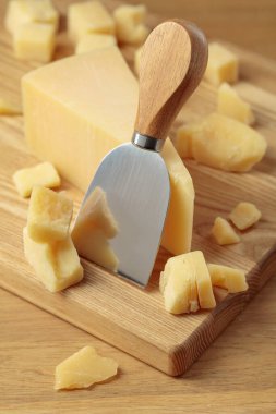 Parmesan cheese and knife on a wooden cutting board.