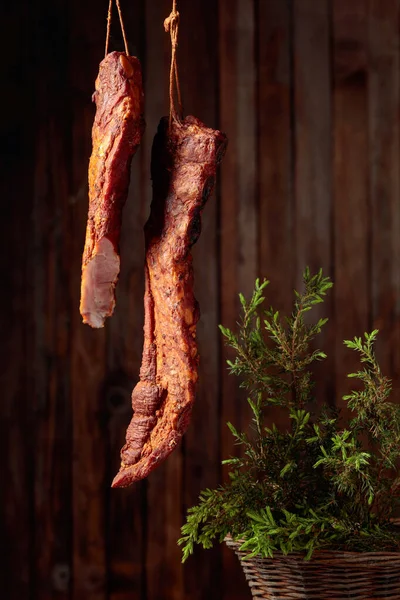 Homemade smoked pork ribs with juniper branches on the background of the old wooden wall.