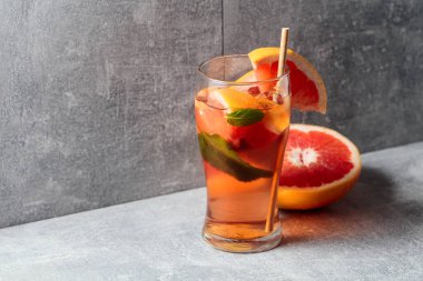 Buzlu, naneli ve greyfurtlu kokteyl. Gri arka planda malzemeleri olan soğuk, ferahlatıcı bir içecek. Boşluğu kopyala.