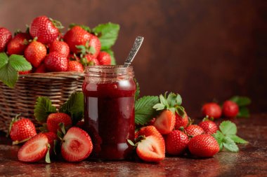 Çilek reçeli ve taze böğürtlen ve eski kahverengi bir masanın üzerinde yapraklar. Boşluğu kopyala.